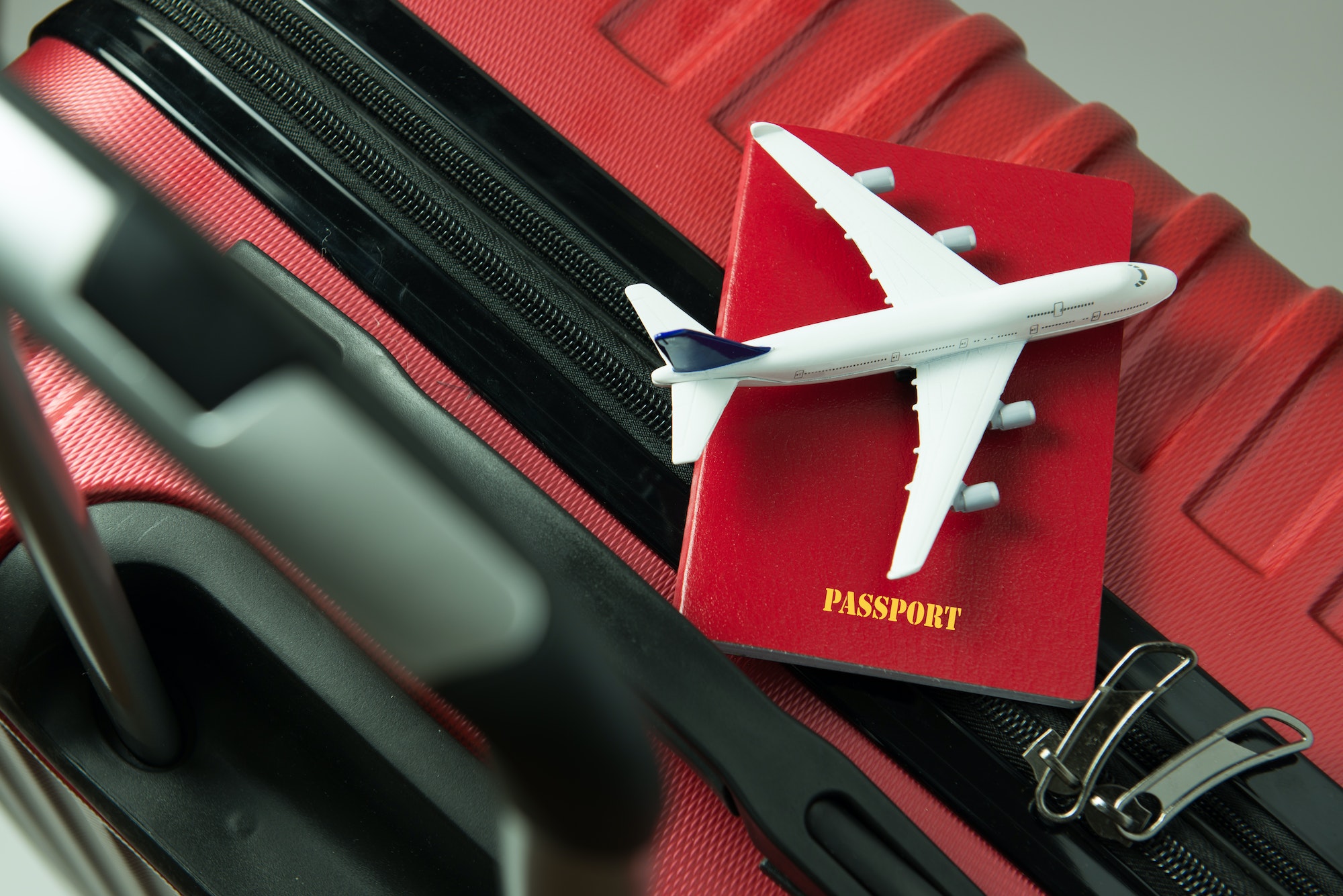 Red passport and airplane model on red luggage